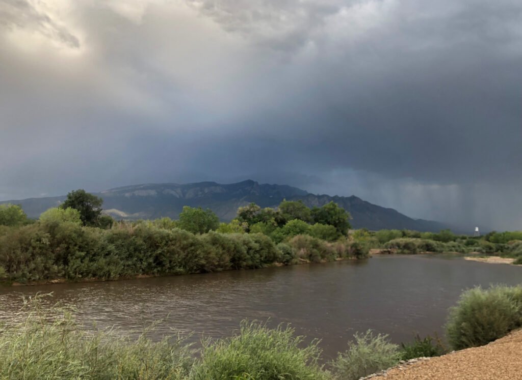 A stormy sky over a river with mountains in the background.