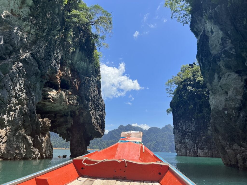 A budget-friendly boat in the water next to a stunning rock formation in thailand.