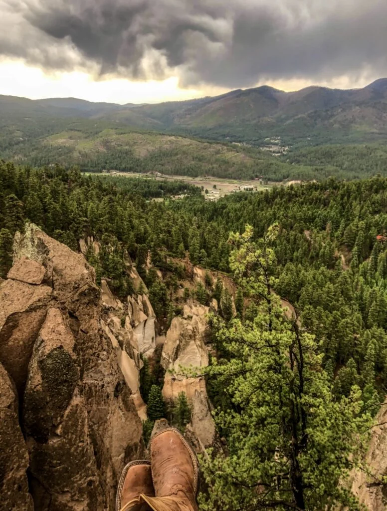 A person's feet on a cliff overlooking a valley.