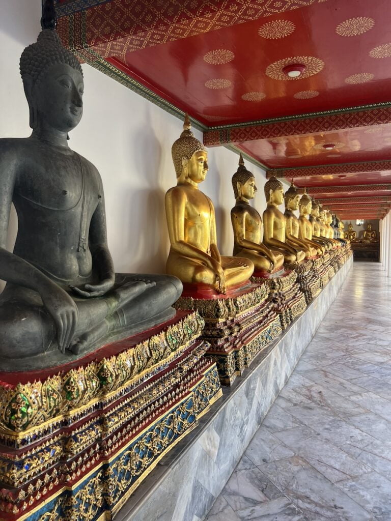 A row of golden buddha statues in a temple in thailand.
