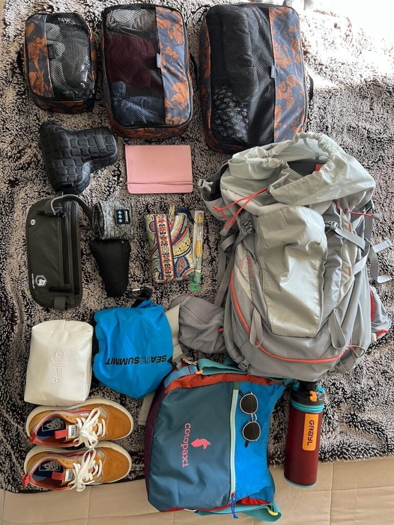 The contents of a backpack from thailand are laid out on a rug.