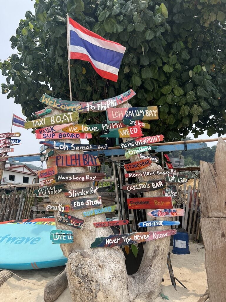 A budget-friendly group of wooden signs on a beach in thailand.